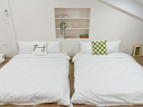 two beds in a room with white walls at Soda White Tainan Homestay in Tainan