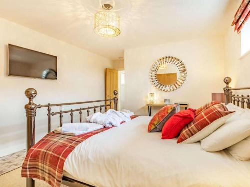 a bedroom with a large bed with red pillows at Stags Barn Saxon Maybank in Sherborne