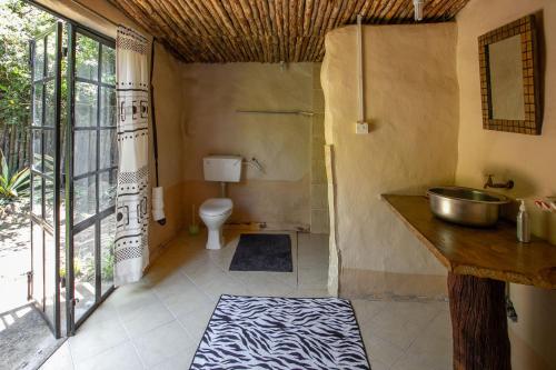 Punda Milias Lodge في ناكورو: حمام مع حوض ومرحاض
