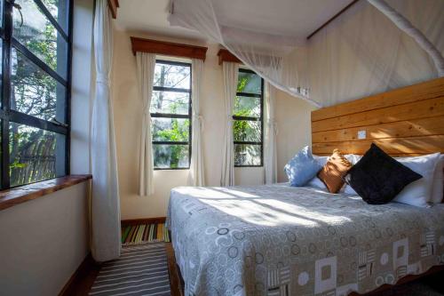 um quarto com uma cama e duas janelas em Punda Milias Lodge em Nakuru