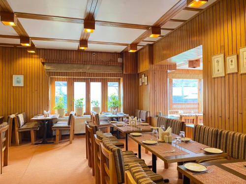 un restaurant avec des murs en bois, des tables et des chaises dans l'établissement Pahalgam Hotel, à Pahalgām