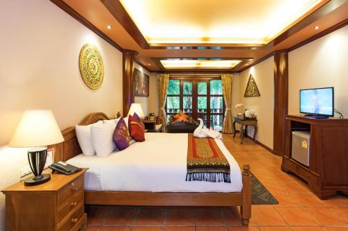 a bedroom with a large bed and a television at Royal Phawadee Village Patong - SHA Plus in Patong Beach