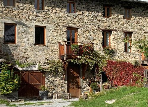 an old stone building with doors and a balcony at La Bousquetière in Jausiers