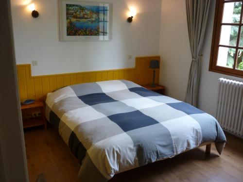 1 cama azul y blanca en una habitación con ventana en Coumenios, en Moulis