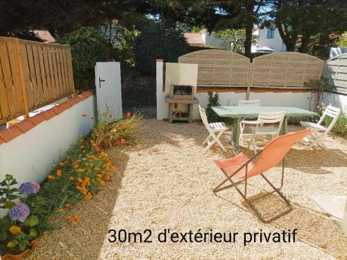 un patio con mesa y sillas en un patio trasero en Maison Bord de mer à Noirmoutier, en Barbâtre