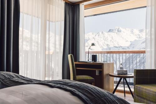 a bedroom with a desk and a view of a mountain at Hotel Schöne Aussicht in Sölden