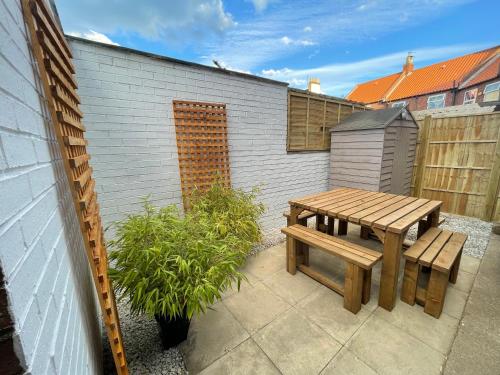 a patio with a wooden bench and a table at The Haven in Hornsea Town Centre in Hornsea