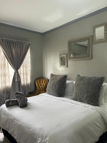 Un dormitorio con una gran cama blanca y una ventana en Jobe Guesthouse, en Pietermaritzburg