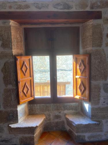 a window in a stone wall with two benches in front at CASA MIRIAM in La Iglesuela del Cid