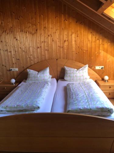 two beds in a room with wooden walls at Haus Bergblick in Kißlegg