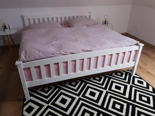 a bed with a white frame and a black and white rug at Farma Opačitá in Valaská Belá