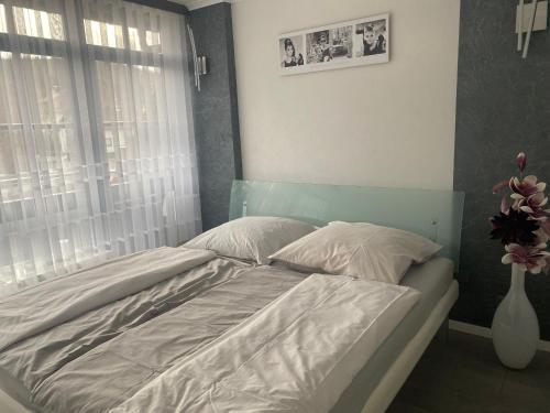 uma cama com lençóis brancos e almofadas num quarto em Luxus 2 Zimmer Ferienwohnung em Lauchheim