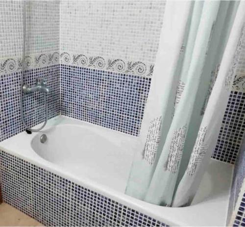 a white bath tub with a shower curtain in a bathroom at sa caleta blava in Cala en Blanes