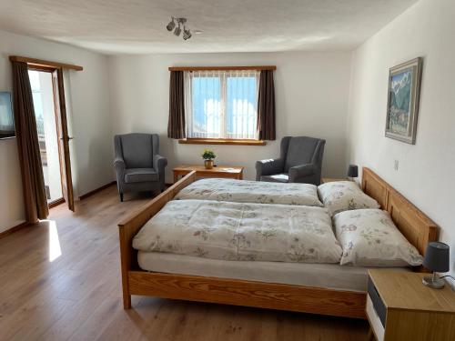 a bedroom with a large bed and two chairs at Hotel La Soglina in Soglio
