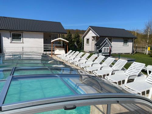 a swimming pool with white chairs and a group at Dolina Wisełka in Wisełka