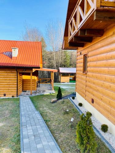 a log cabin with an orange roof and a yard at Borówkowy Jar in Ropienka