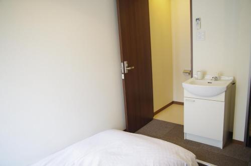 een kleine badkamer met een wastafel en een bed bij Suminoyu Hotel in Nagoya