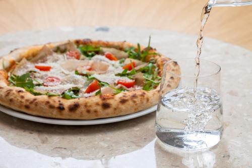 a pizza sitting on a table next to a glass of water at Apartamenty MonteVerde w Świeradowie-Zdroju in Świeradów-Zdrój