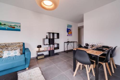 a living room with a dining room table and a blue couch at Le 305 - T3 with garage and beautiful terrace in Annecy