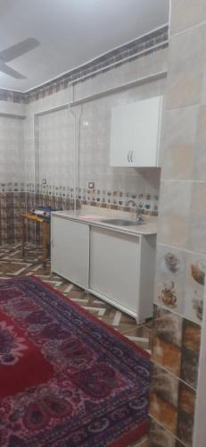 a kitchen with white cabinets and a table and a rug at apartment for rent in Luxor