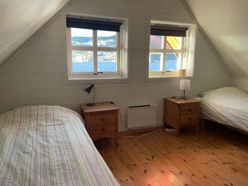 a attic bedroom with two beds and two windows at Spacious apartment with view over the trondheimfjord in Vangshylla