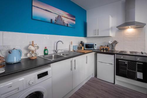 een keuken met witte kasten en een blauwe muur bij Bank Street Apartment 8 in Blackpool