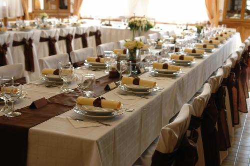 a long row of tables with white tablecloths and glasses at Koller Panzió in Bonyhád