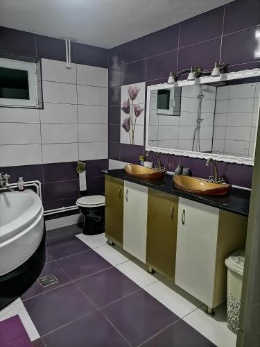 a purple bathroom with two sinks and a toilet at Pensiunea Melissa in Măceşu de Jos
