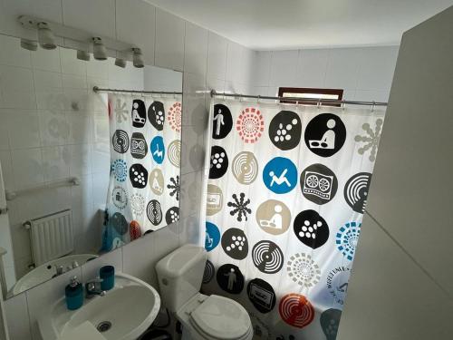 a bathroom with a shower curtain with a toilet and a sink at Depto Maitencillo frente al Mar - Costamai in Maitencillo