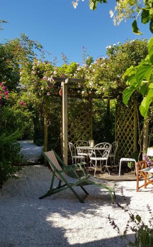 un patio avec une table et des chaises sous une pergola dans l'établissement Au 3 La Cour à Tôt, à Regnéville-sur-Mer