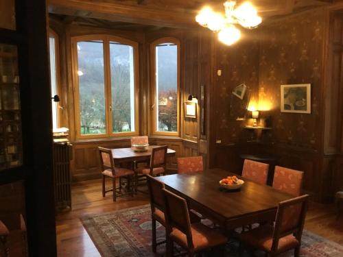 a dining room with a table and chairs and windows at Villa Meyriem in Mouthier-Haute-Pierre