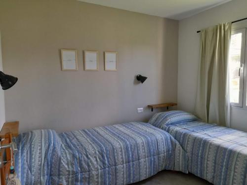 1 dormitorio con 2 camas y ventana en Casas Tomillo Silvestre en Sierra de la Ventana