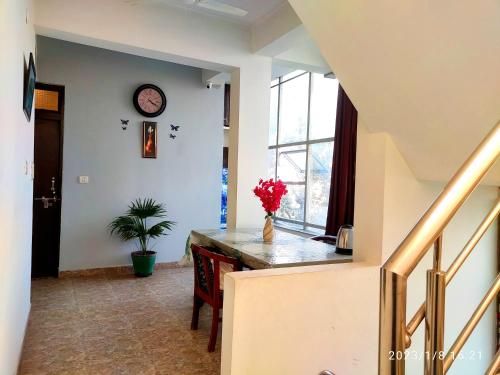 a hallway with a table and a clock on the wall at Max Guest House in Agra