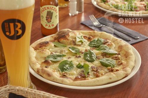 a pizza on a plate on a table with a beer at Hotel Jedlinka in Jedlina-Zdrój