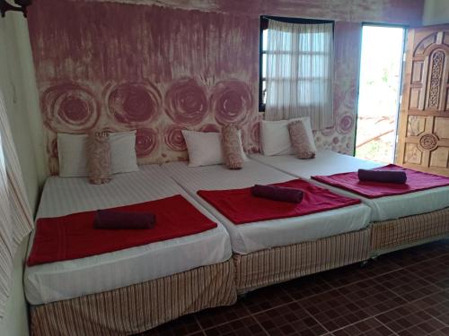 a bedroom with a large bed with two red sheets at Bang Son Golden View in Baan Khai