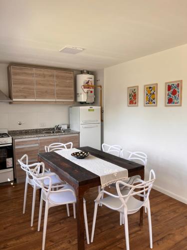 a kitchen with a wooden table and white chairs at Cabañas del lago in El Calafate