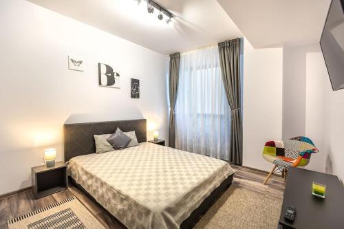 een slaapkamer met een bed, een raam en een stoel bij Modern apartment with city-view near Poiana Brasov in Braşov