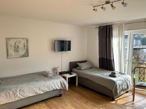 a bedroom with two beds and a tv on the wall at Apartment am Kurpark in Bad Oeynhausen