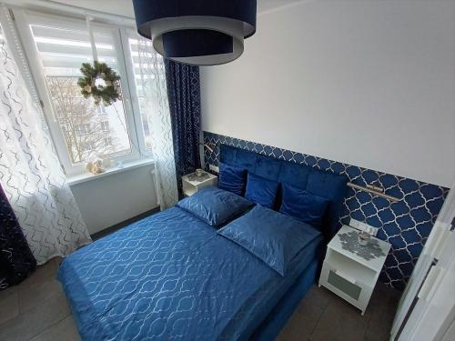 a bedroom with a blue bed and a window at Kryształowy apartament in Tarnowskie Góry