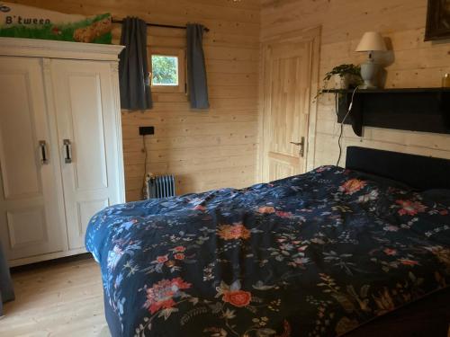 een slaapkamer met een bed met een blauw dekbed bij Berghut in Doorn