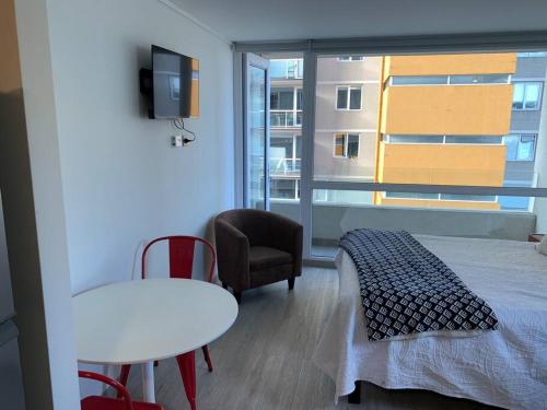 a bedroom with a bed and a chair and a window at Departamento studio. in Temuco