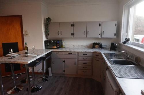 a kitchen with white cabinets and a sink and a counter at No1 Dalbeg, a Hebridean Escape and your Adventure. in Dalebeg
