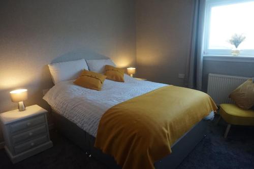 a bedroom with a bed with yellow sheets and a window at No1 Dalbeg, a Hebridean Escape and your Adventure. 