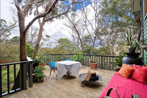 een patio met een tafel en stoelen en een hek bij The Black Cockatoo - Secret Garden Treetops Home in Katoomba