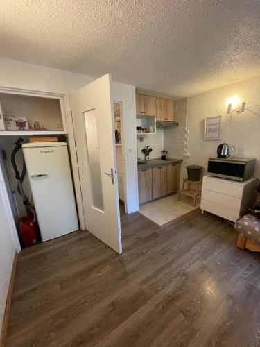 Il comprend un salon avec une cuisine et une porte blanche. dans l'établissement Appt chaleureux 2 - 4 personnes au pied des pistes - draps et linges de toilette non fournis - ménage non inclus - attention rénovation de façade actuellement, à La Mongie