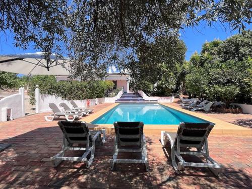a group of lounge chairs and a swimming pool at Beautiful private Villa with pool, Boliqueime, Loulé in Boliqueime