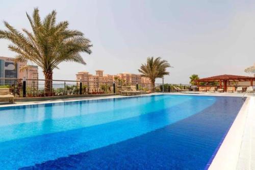 杜拜的住宿－1 Bed Apartment with Sea View, Pool, Gym & Free Parking in Dubai Marina，一座种植了棕榈树和建筑的大型蓝色游泳池