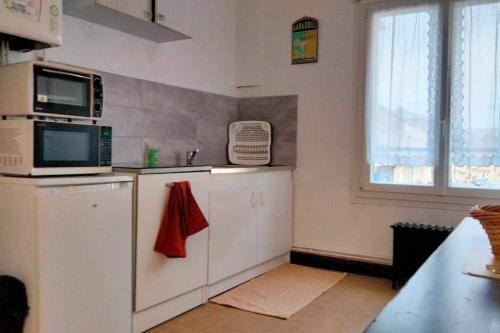 d'une cuisine avec des placards blancs, un four micro-ondes et une fenêtre. dans l'établissement Appartement 57 m2 proche plage et Nausicaa, à Boulogne-sur-Mer