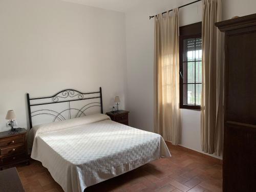 um quarto com uma cama branca e uma janela em Chalet El Madroño, en el Castillo de las Guardas. em Minas del Castillo de las Guardas