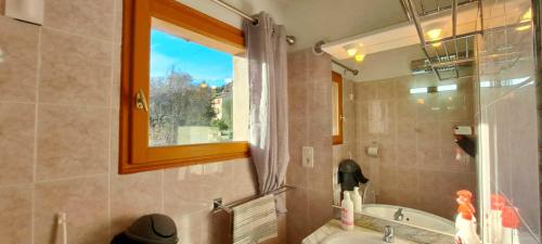 ein Bad mit einem Waschbecken, einer Badewanne und einem Fenster in der Unterkunft Locations-06 La Maison Du Paysan in Le Bar-sur-Loup